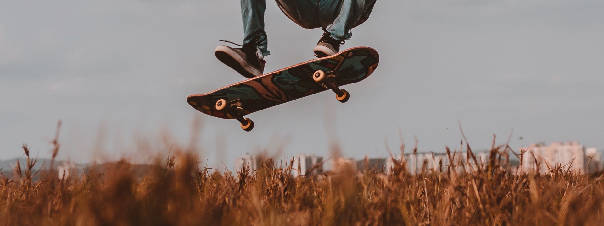 Foto einer springenden Person auf dem Skateboard, auf welchem nur die Füße und das Skateboard zu sehen sind.